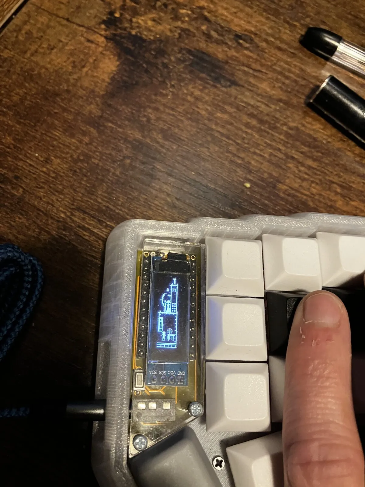 The opposite half of the same keyboard, its OLED rendering a matching city scene.