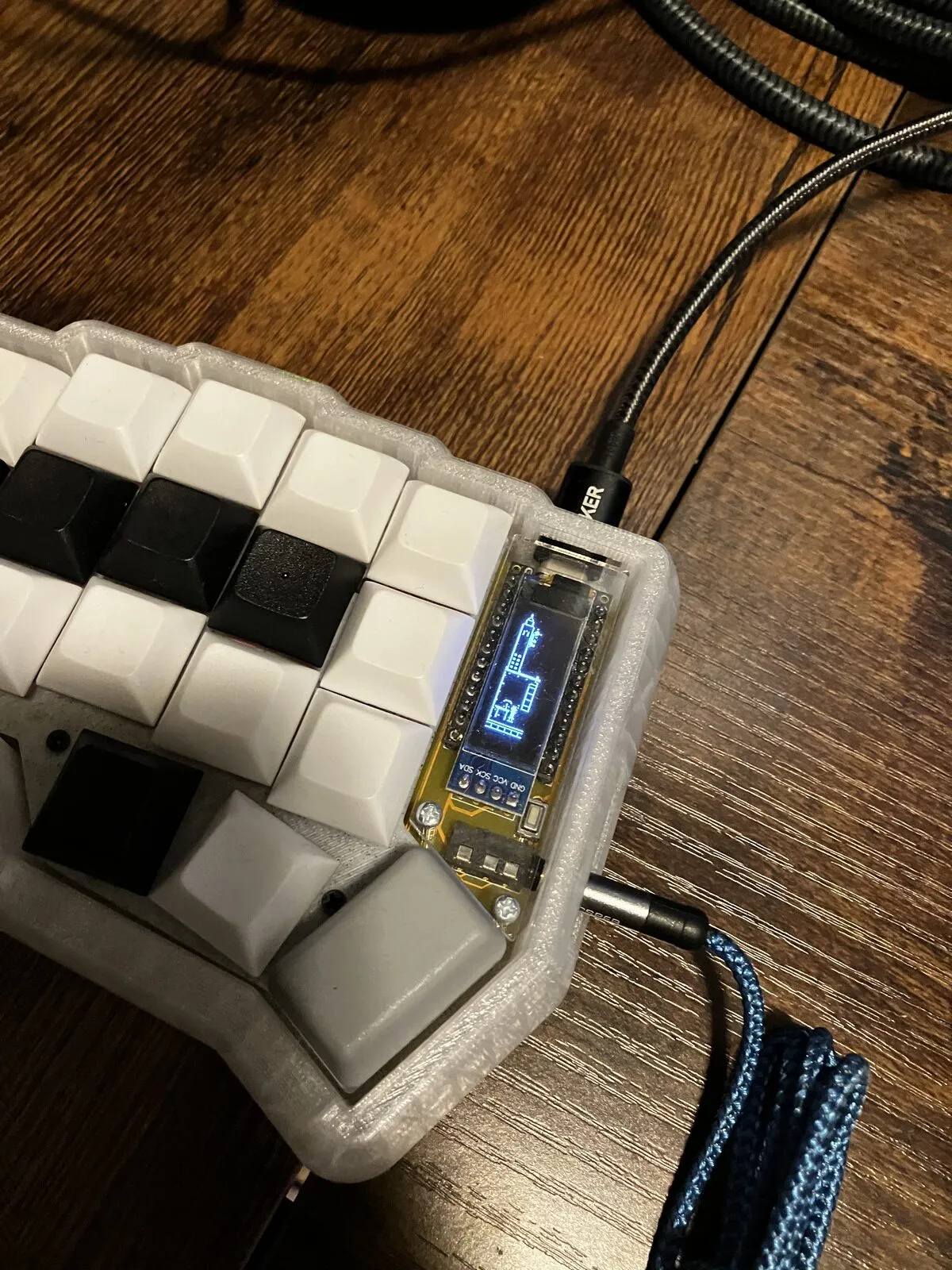 The full master half in its translucent printed case, OLED lit, showing the key layout and thumb cluster.