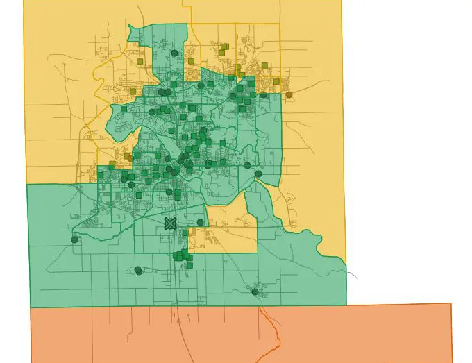 A map of Cedar Rapids census tracts with a green center, yellow tracts around it, an orange band of tracts along the south edge, station and shelter markers, and a crossed marker south of the center.
